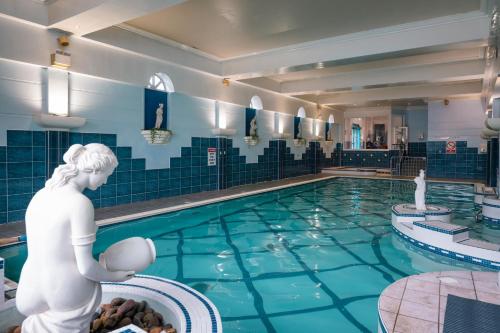 a swimming pool with a statue of a woman in the water at Castle Hotel Macroom in Macroom