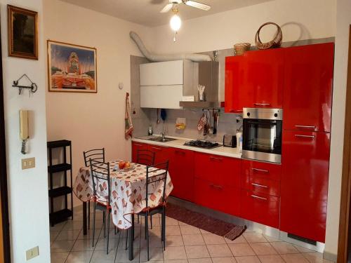 une cuisine avec des placards rouges et une table avec des chaises dans l'établissement 2 bedrooms apartement with sea view furnished terrace and wifi at Olbia 5 km away from the beach, à Olbia