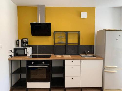 a kitchen with a counter with a sink and a refrigerator at Maison de village family friendly - Doucier in Doucier