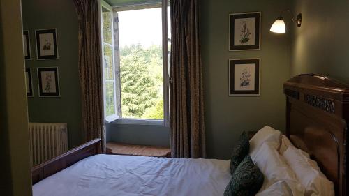 a bedroom with a bed and a large window at L'ancienne Gendarmerie in Saint-Laurent-sur-Gorre