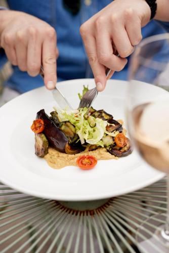 a person eating a plate of food with a fork and knife at The Queen's Head in Broad Chalke