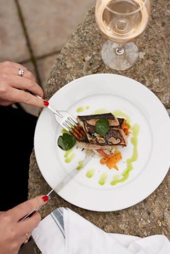 a person holding a plate of food with a fork and knife at The Queen's Head in Broad Chalke
