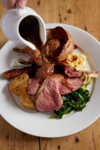 a plate of food with meat and gravy on a table at The Queen's Head in Broad Chalke