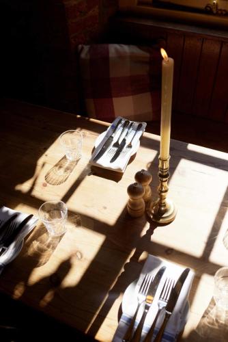 a table with a candle and plates and glasses on it at The Queen's Head in Broad Chalke