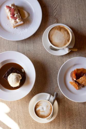 a table with plates of desserts and a cup of coffee at The Queen's Head in Broad Chalke