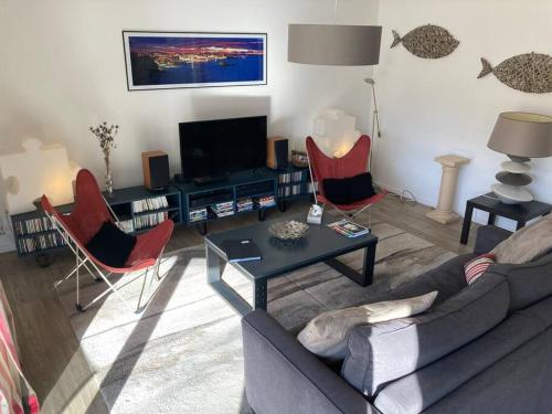 ein Wohnzimmer mit einem Sofa, Stühlen und einem TV in der Unterkunft Appart Hypercentre Biarritz - PKG / WIFI / 4-6 Personnes in Biarritz