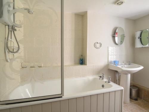 a bathroom with a shower and a tub and a sink at Riverbank in Axminster