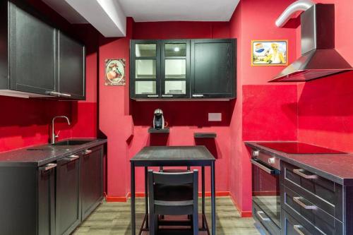 ボローニャにあるCorte de’ Galluzzi My Home For Youの赤いキッチン(黒いキャビネット、黒いスツール付)