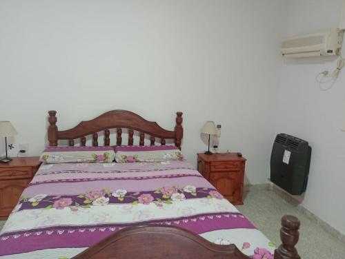 Concordia的住宿－El remanso，一间卧室配有一张带紫色床单的木床
