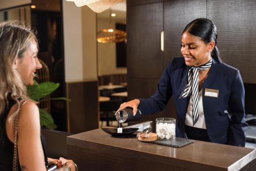 a woman standing at a counter talking to a woman at Best Western Plus Hôtel Massena Nice in Nice
