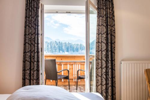 a bedroom with a bed and a view of a balcony at Hotel Antholzerhof in Anterselva di Mezzo