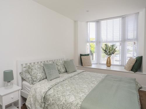 biała sypialnia z łóżkiem i oknem w obiekcie Swn Y Mor Sound of the Sea w mieście Criccieth