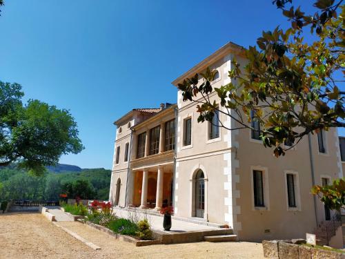 ein großes weißes Gebäude mit einem Baum im Vordergrund in der Unterkunft Hôtel Villa Walbaum in Vallon-Pont-dʼArc