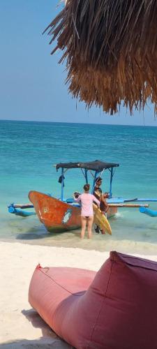 a woman standing next to a boat on the beach at Suci's Friendly Apartments in Mataram