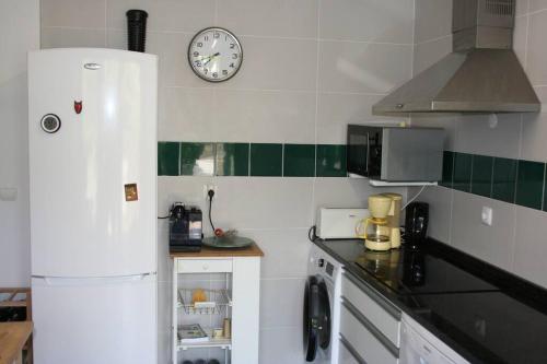 a kitchen with a refrigerator and a clock on the wall at Quinta do Enxertado in Vila Real