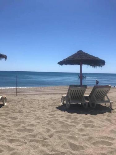 two chairs and an umbrella on a beach at Best location in Fuengirola! in Fuengirola