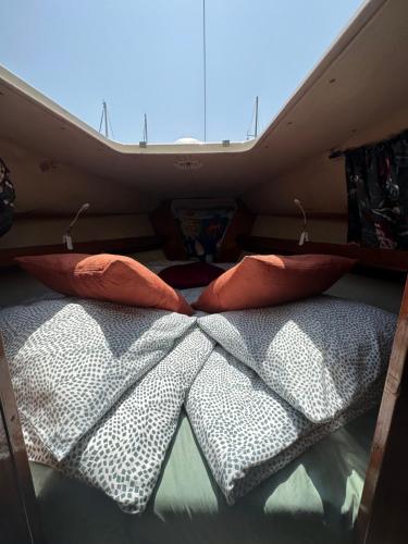 1 cama en la parte trasera de una caravana con 2 almohadas en Barco el viento en Barcelona