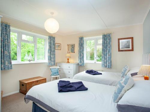 a bedroom with two beds and two windows at Sweets Close in St Austell