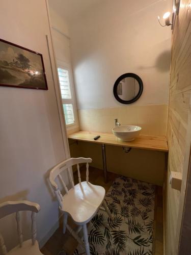 ein Badezimmer mit einem Waschbecken, einem Spiegel und einem Stuhl in der Unterkunft Chez Léandre in Vitry-le-François
