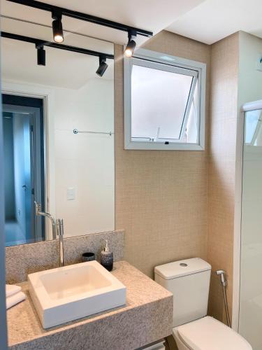 a bathroom with a sink and a toilet and a mirror at PALMAS EXPERIENCE - APARTAMENTO VISTA LAGO, próximo ao shopping in Palmas