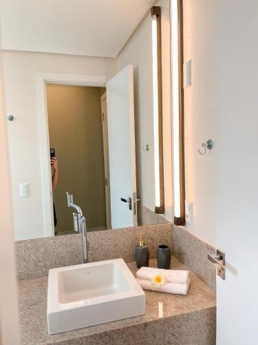 a person taking a picture of a sink in a bathroom at PALMAS EXPERIENCE - APARTAMENTO VISTA LAGO, próximo ao shopping in Palmas