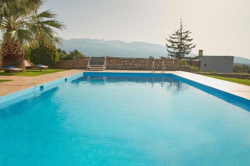 a large blue swimming pool in a yard at Dreamscape Residences - Villa Rafaella in Epáno Kefalás
