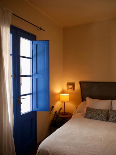 a bedroom with a blue door and a bed at Hostal de la Plaça - Hotel Boutique in Cabrils
