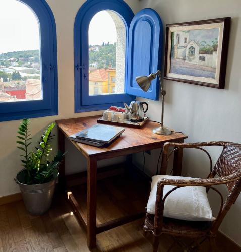 a desk with a lamp and a chair in a room with two windows at Hostal de la Plaça - Hotel Boutique in Cabrils