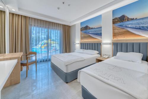 a hotel room with two beds and a desk at Kahya Hotel in Alanya