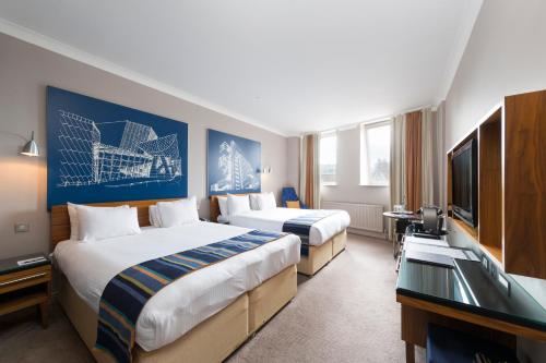 a hotel room with two beds and a flat screen tv at The Townhouse Manchester in Manchester