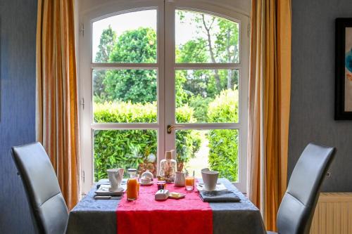 een tafel met een rood tafelkleed en een groot raam bij La Fontaine Dort in Tessy-sur-Vire