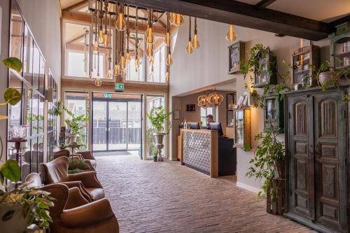 einen Gang eines Restaurants mit Ledersesseln und Pflanzen in der Unterkunft Hotel De Walvisvaarder in Lies