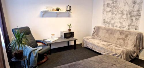 a living room with a chair and a table with a tv at Przytulny prywatny pokój w ścisłym centrum Warszawy Pokój 4 in Warsaw