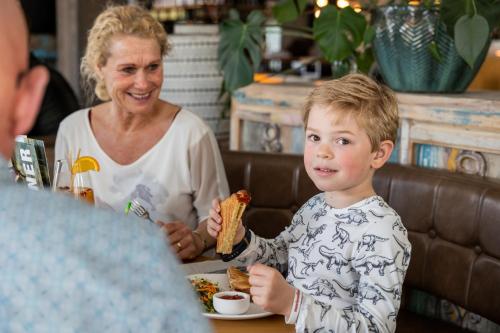a young boy eating a sandwich with a woman at Hotel De Walvisvaarder in Lies