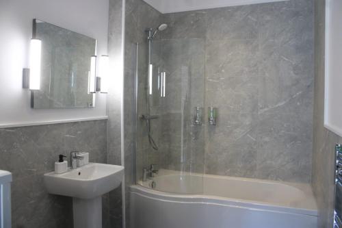 a bathroom with a tub and a sink and a shower at Fenwick Sunrise Hotel in Liverpool