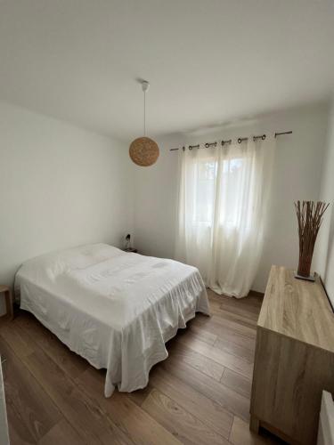 a white bedroom with a bed and a window at Appartement Presqu île de Giens in Hyères