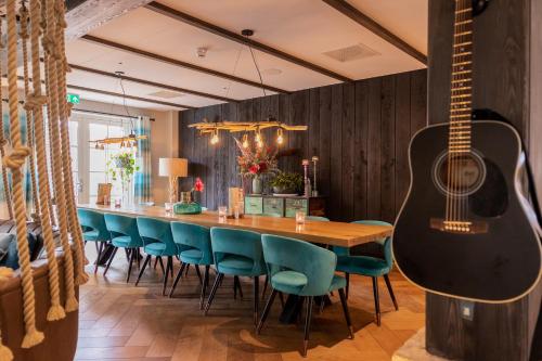 a dining room with a table and a guitar at Hotel De Walvisvaarder in Lies