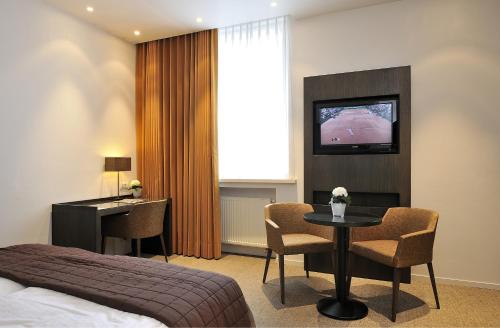 a hotel room with a bed and a table and a television at Parkhotel Kortrijk in Kortrijk