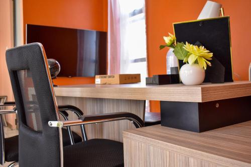 a desk with a chair and a vase with flowers on it at Forefront Self-Catering Apartments in Kitwe