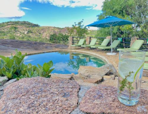a glass of water sitting next to a pool at Big Cave Camp in Matopos