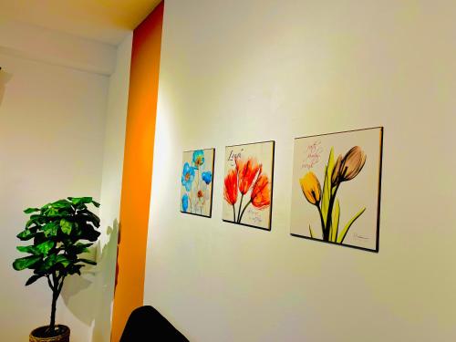 four paintings of flowers on a wall in a room at P1 PineComfyStay Waterpark 7pax Ipoh in Kampong Pinji