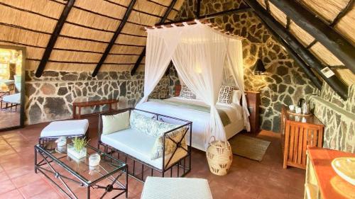 1 dormitorio con 1 cama y 1 silla en una habitación en Big Cave Camp en Matopos