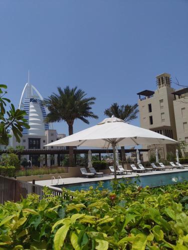 una piscina con sillas, sombrillas y edificios en Ultimate Stay / Next to Burj Al Arab / Upscale Luxury / Amazing Pool with a View / Perfect Holiday / Madinat Jumeirah / 2 BDR, en Dubái