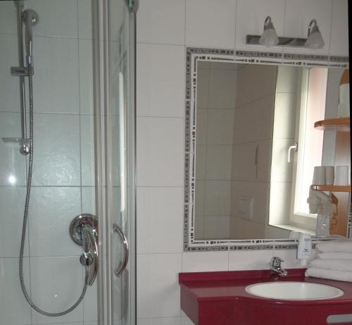 a bathroom with a shower and a sink and a mirror at Park Hotel Villa Etschland in Plaus