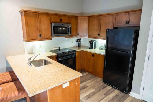 a kitchen with a black refrigerator and wooden cabinets at The Appalachian at Mountain Creek in Vernon