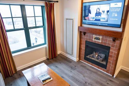 a living room with a fireplace and a flat screen tv at The Appalachian at Mountain Creek in Vernon