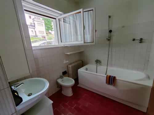 baño con bañera, aseo y ventana en Il Terrazzo Sulle Dolomiti, en Cibiana