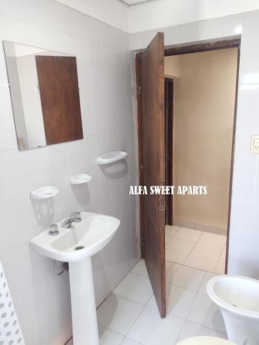 a white bathroom with a sink and a mirror at ALFA SWEET APARTS in Formosa