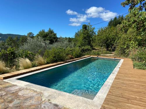 - une piscine dans une cour avec une terrasse en bois dans l'établissement Belle de Nuit, à Malbosc