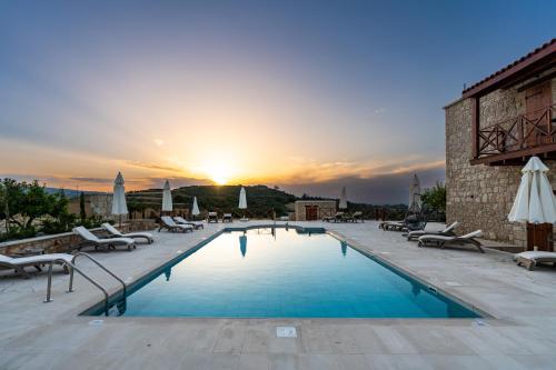 a pool with chairs and a sunset in the background at Harma Traditional Boutique Suites in Paphos City